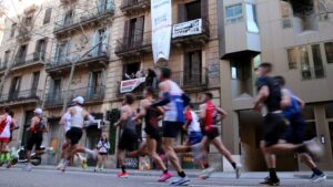 Veïns d’un bloc de l’Eixample denuncien assetjament immobiliari amb una pancarta al pas de la Marató