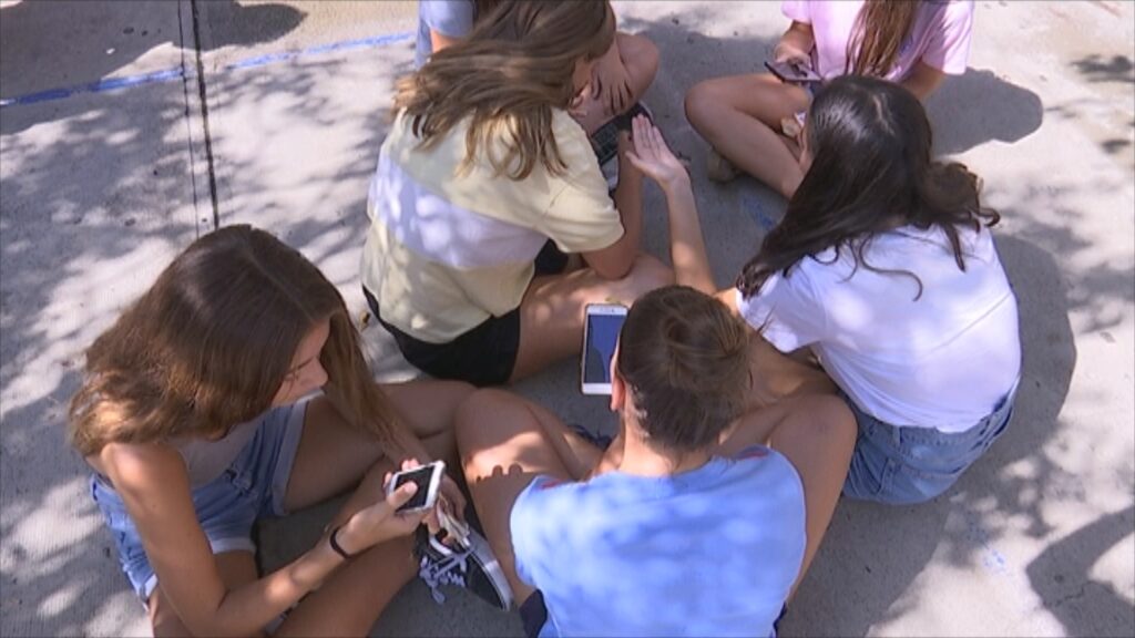 Menors mirant el mòbil al pati de l'escola